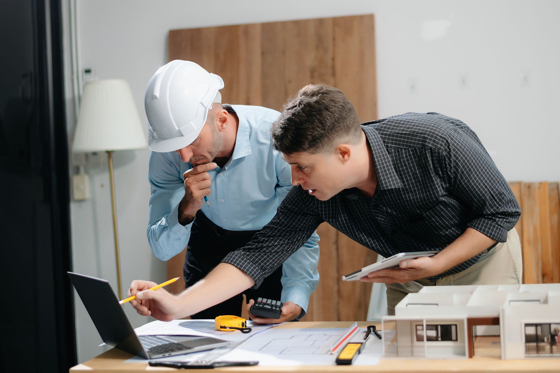 two men with calculators looking at a building plan